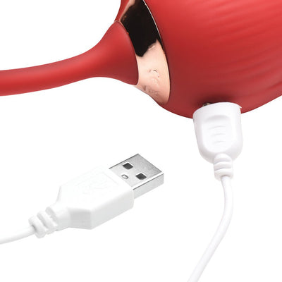 Close-up of red silicone rose vibrator connected to a white USB charging cable on a white background.