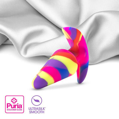 Colorful striped silicone vibrating plug with tapered head on white silk fabric background, Puria Ultrasilk smooth material.