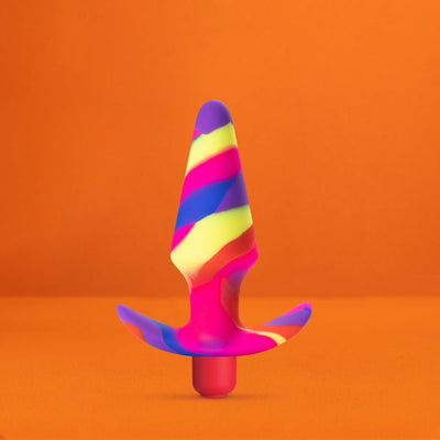 Colorful silicone vibrating plug with tapered tip and flared base against an orange background.