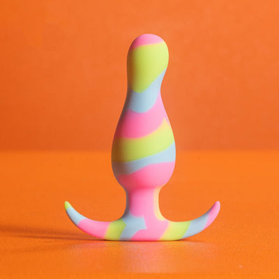 Colorful silicone plug with lime, pink, and blue swirls, featuring a tapered shape and curved base on an orange background.