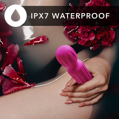 Hand holding a pink waterproof wand vibrator submerged in water with red flower petals around.