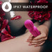 Hand holding a pink waterproof wand vibrator submerged in water with red flower petals around.
