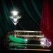 Emerald green curved vibrator on gold tray with crystal accents and a martini glass against velvet backdrop
