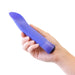 Hand holding a sleek purple curved vibrator with a smooth satin finish and faceted base.
