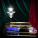 Blush Oh My Gem Mystery Sapphire vibrator on a gold tray with a martini glass and decorative gems against velvet drapes.