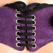 Close-up of purple leather corset harness with black braided laces threaded through metal eyelets.