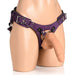 Purple leather corset harness with adjustable straps and metal o-ring, displayed on a mannequin torso with a flesh-toned dildo attached.