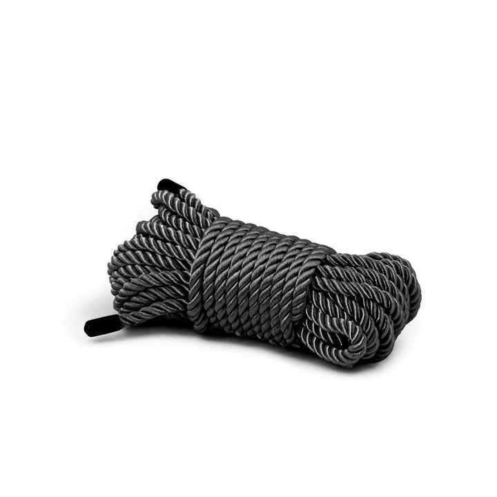 Coiled black synthetic bondage rope with a smooth, twisted texture, designed for comfort and durability.