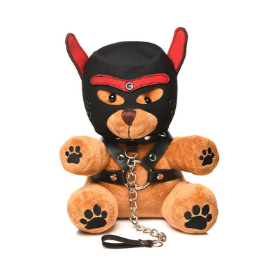 Plush light peach teddy bear wearing a black and red puppy mask and faux leather harness with metal chain leash.