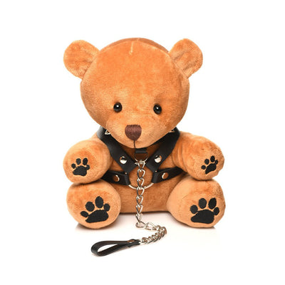 Light brown plush teddy bear wearing a black faux leather harness with metal rings and a chain leash accessory.