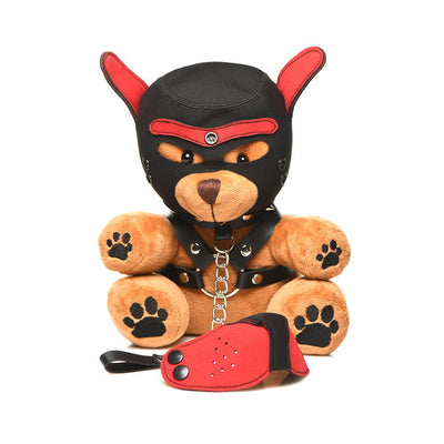 Light peach plush bear wearing a black and red puppy mask and faux leather harness with metal rings, sitting with a red and black accessory.