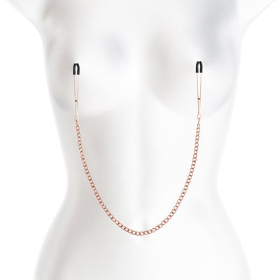 Rose gold adjustable nipple clamps with black silicone tips connected by a matching chain on a white mannequin torso.