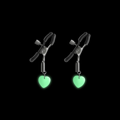 Gunmetal adjustable nipple clamps with soft silicone tips and glowing green heart charms on black background.