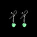 Gunmetal adjustable nipple clamps with soft silicone tips and glowing green heart charms on black background.