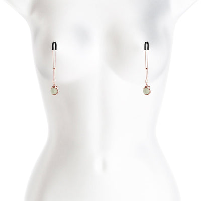 Rose gold adjustable nipple clamps with black silicone tips displayed on a white mannequin torso.