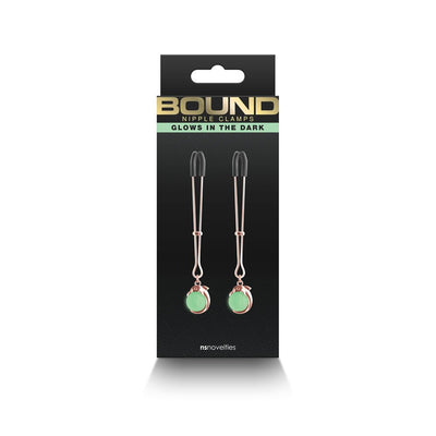 Rose gold adjustable nipple clamps with glow-in-the-dark green accents and soft black silicone tips in black packaging.
