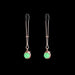 Rose gold adjustable nipple clamps with soft black silicone tips and green decorative accents on a black background.