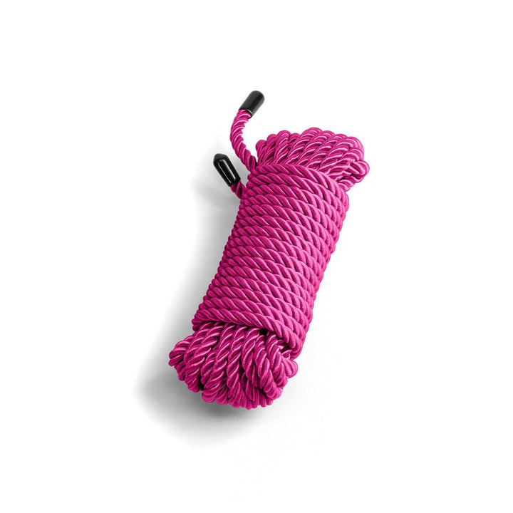 Coiled vibrant pink soft rope with black capped ends, designed for comfortable and creative intimate use.