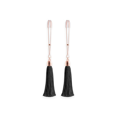 Pair of rose gold adjustable nipple clamps with soft silicone tips and black tassel accents on a white background.