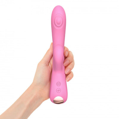 Hand holding a pink dual stimulator with ergonomic design and control buttons on the handle against a white background.