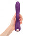 Hand holding a sleek purple dual stimulator with ergonomic design and control buttons on the handle.