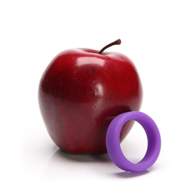 Purple soft silicone ring displayed next to a shiny red apple on a white background.