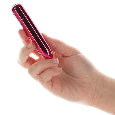 Hand holding a compact, metallic pink bullet vibrator with a pointed tip and smooth finish.