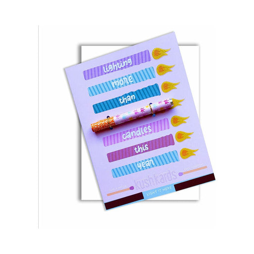 Purple greeting card with colorful flame designs and a multicolored metal one-hitter pipe attached, reading lighting more than candles this year.