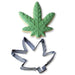 Cannabis leaf-shaped cookie cutter with a decorated green leaf cookie on a white background.