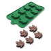 Green silicone mold with 11 cannabis leaf cavities and five chocolate leaves made from the mold displayed on a white background.