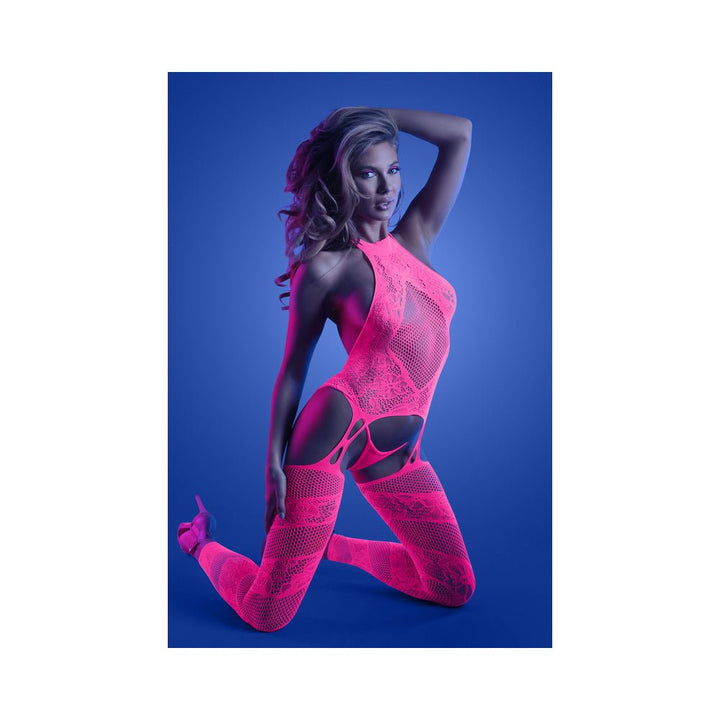 Model kneeling in neon pink halter bodystocking with matching G-string against blue background