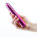 Hand holding a sleek, metallic pink 7-inch rechargeable vibrator with a smooth, rounded design.