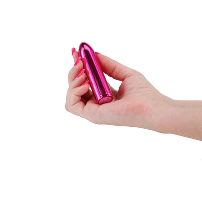 Hand holding a sleek, metallic pink Chroma Petite Bullet vibrator against a white background.