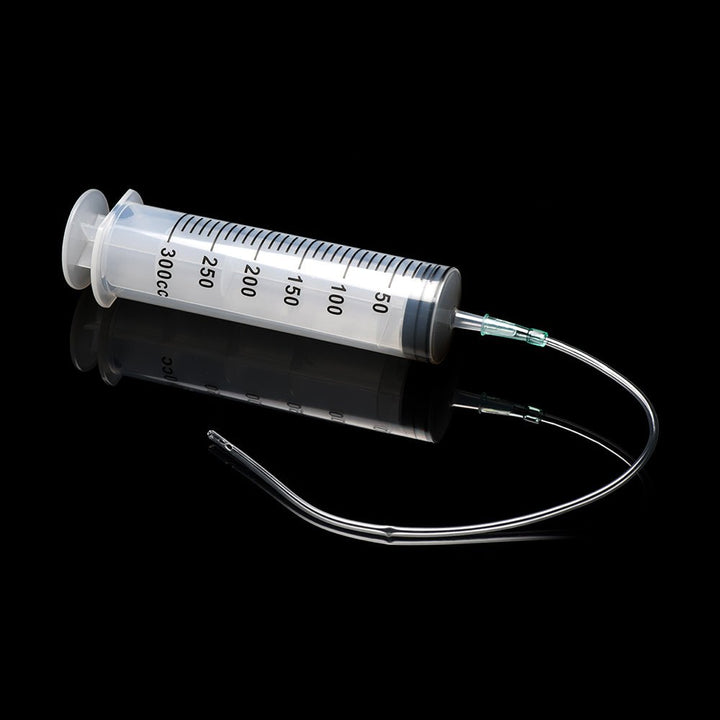 Clear 300ml enema syringe with flexible silicone tube and tapered tip on black reflective surface.