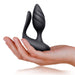 Hand holding a black silicone dual-motor couples toy with contoured textured plug and flexible shaft.