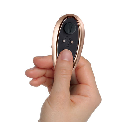 Hand holding a rose gold and black remote control for a couples' vibrator with a single button on top.