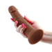 Hand holding a brown 7-inch realistic silicone vibrating dong with a suction base and pink nail polish.