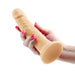 Hand holding a flesh-toned 7-inch realistic vibrating dildo with a suction base on a white background.