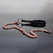Rose gold chain leash with black vegan leather wrist strap and metal COQUETTE charm on reflective surface.