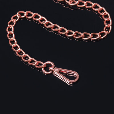 Rose gold metal chain leash with a sturdy clip on a black reflective surface.