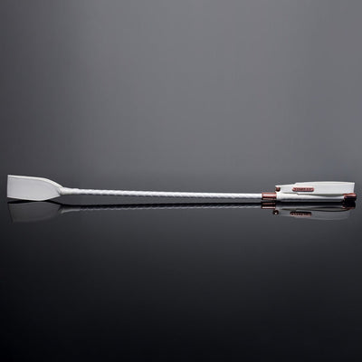 White vegan leather crop with braided handle and rose gold metal accents on reflective black surface