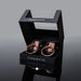 Coquette black vegan leather cuffs with rose gold metal rings in a black display box with clear lid and white lettering.