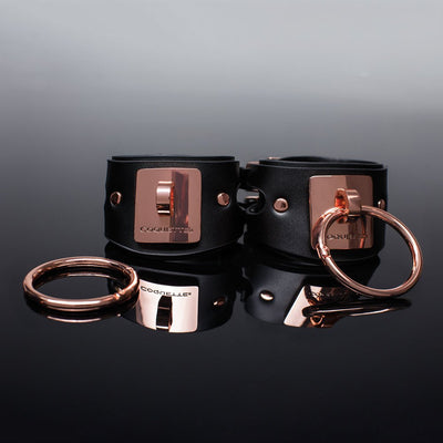 Black vegan leather cuffs with rose gold metal plates and detachable rings, featuring adjustable buckle closures.