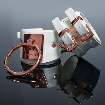 White vegan leather wrist cuffs with rose gold metal buckles and large O-ring, Coquette engraved plate, adjustable straps.