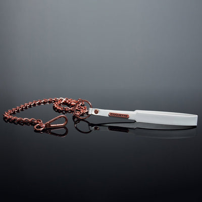 White vegan leather wrist strap leash with rose gold chain and metal clasp on reflective black surface