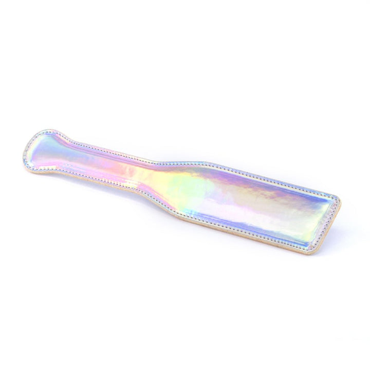 Rainbow holographic vinyl bondage paddle with stitched edges and a flat handle on white background.