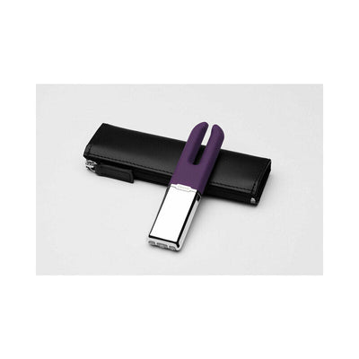 Purple dual-pronged clitoral stimulator with silver base resting on a black zippered leather pouch.