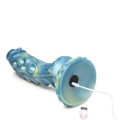Blue and yellow iridescent silicone dildo with textured shaft and suction cup base, shown with USB charging cable connected.