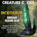 Green and black textured dinosaur-themed silicone dildo with clawed feet and a curved tail on a forest floor background.