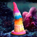 Rainbow-colored silicone tentacle dildo with textured suckers and suction cup base against an underwater octopus background.